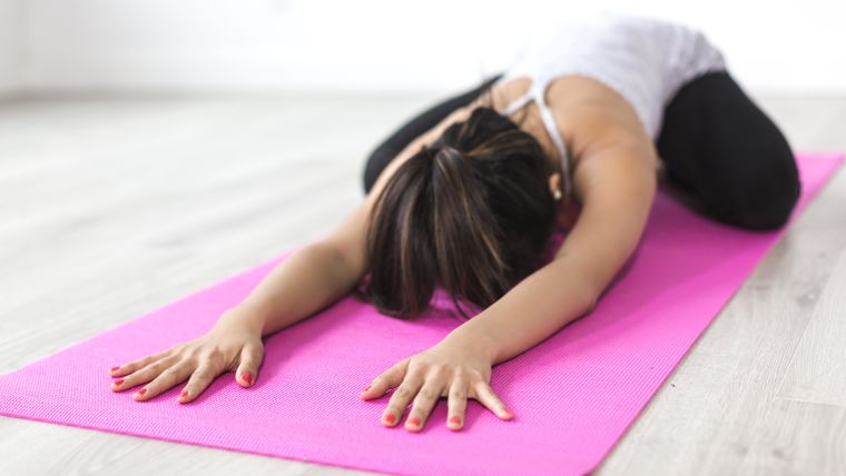 Female yoga student practising yoga on a mat.
