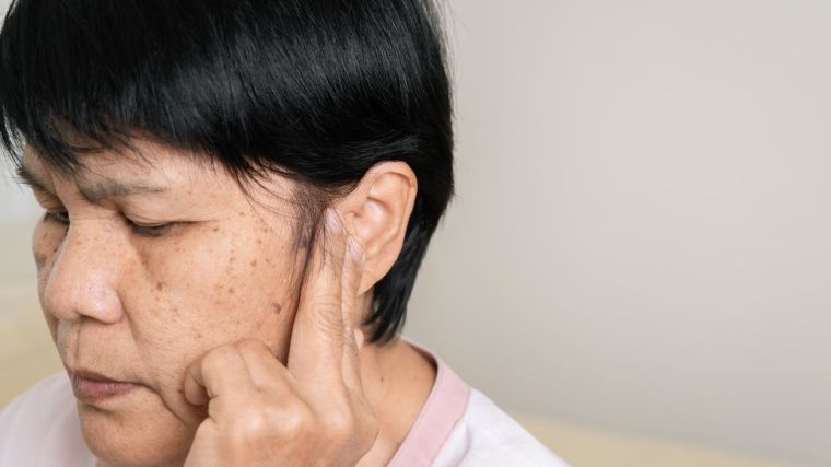 Older asian woman with ear troubles