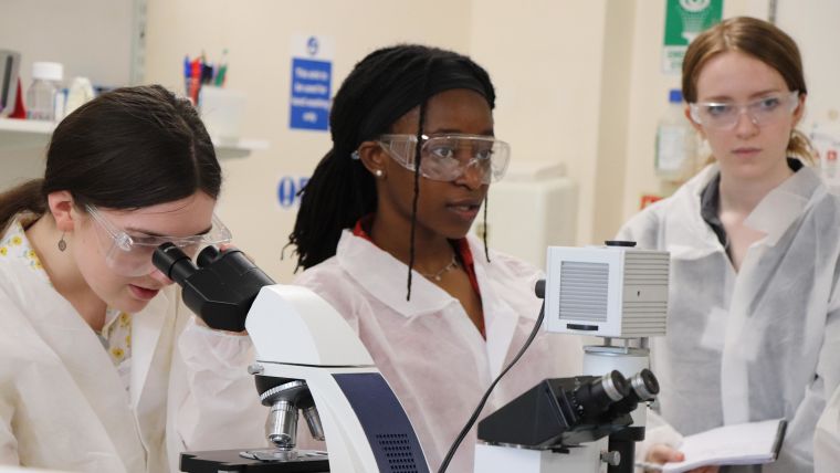 Three female students carrying out microscope lab experiments